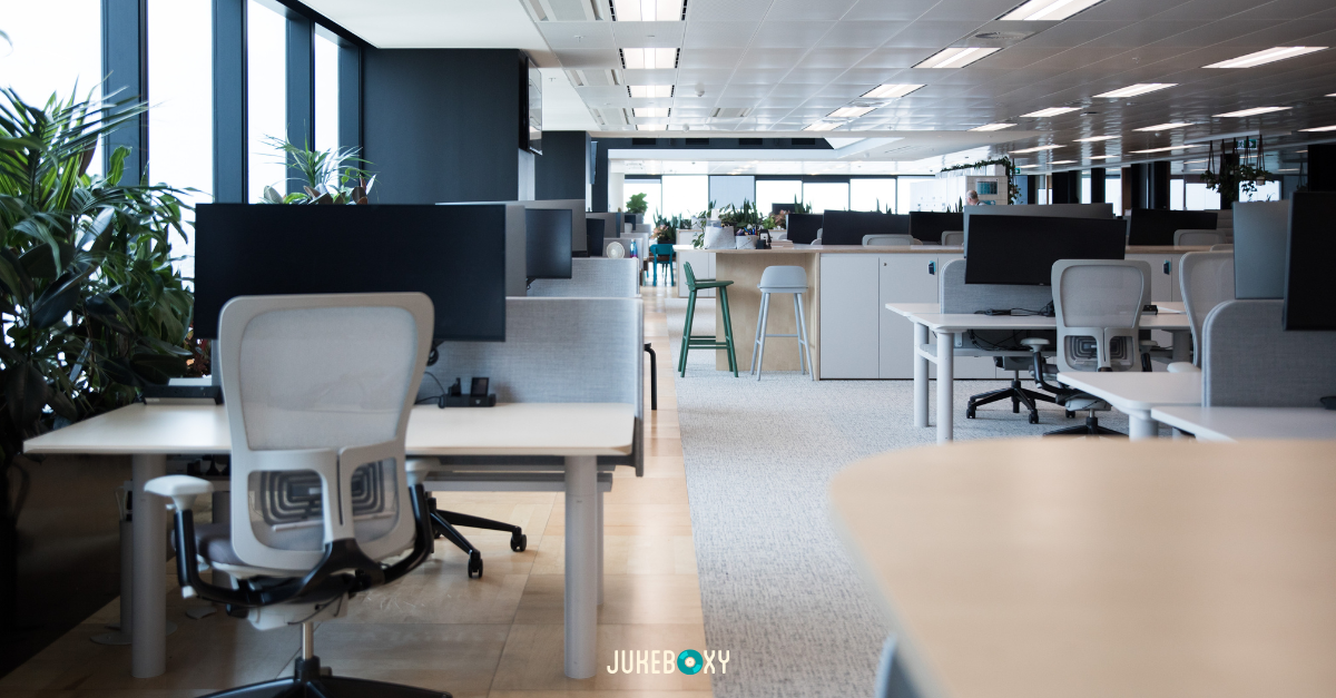 Modern 2026 open-plan office with biophilic design and acoustic wall panels, creating a productive environment for background music.