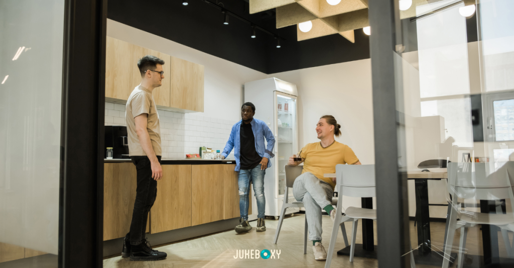 Diverse group of employees in a warm, multi-level modern office lounge collaborating and socializing.