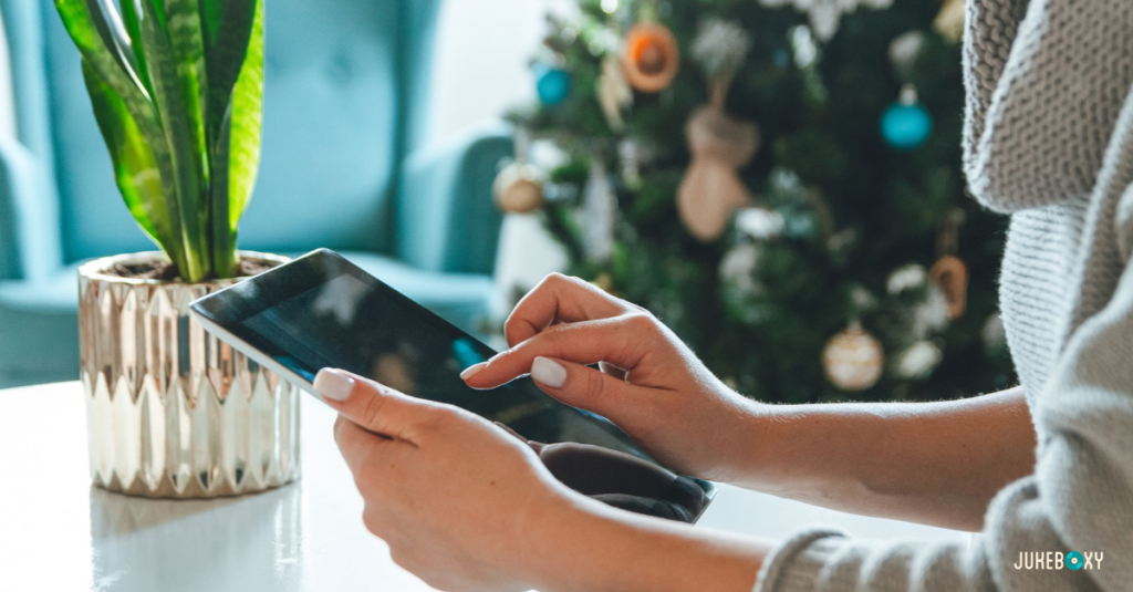 Business owner scheduling holiday music on a tablet next to a Christmas tree